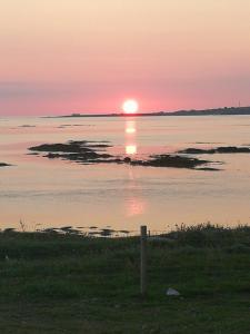 a sunset over a body of water with the sun setting at An Taigh Mòr in Eriskay