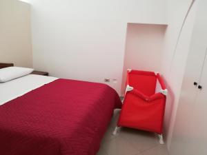 una sedia rossa seduta accanto a un letto in una stanza di Zia Betta House a Carovigno