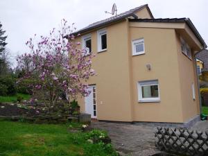 una casa con un árbol floreciente delante de ella en Ferienhaus im Nordschwarzwald, en Pforzheim