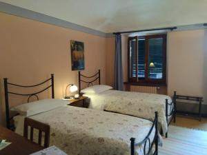 a bedroom with two beds and a table and a window at Il Glicine in Zimone