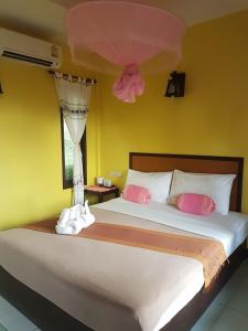 una camera da letto con un letto con cuscini rosa e bianchi di Paradise Bungalows a Ko Chang
