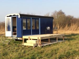 Una pequeña casa azul sentada en un campo en Sitting at the Bay en Zuiderwoude