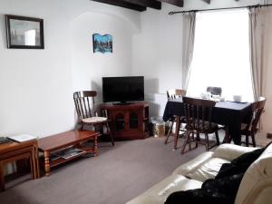 a living room with a couch and a table and a television at Lupine Cottage in Whitby