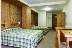 dwa łóżka w pokoju z drewnianymi ścianami w obiekcie Hotel Valdotain w mieście Villeneuve