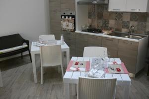 アヴェトラーナにあるIl Fenicotteroの白いテーブルと椅子付きのキッチン、シンク付きのキッチン