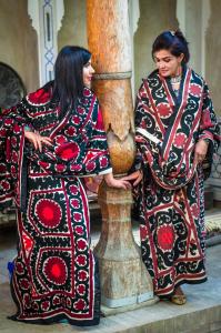 Dos mujeres están de pie junto a un árbol en ANTICA Family Guest House, en Samarkand