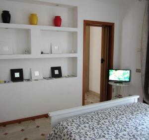 a bedroom with a bed and a tv and shelves at Zara Apartment in Treviso