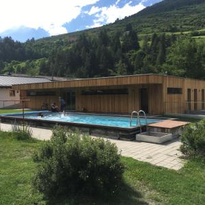 a building with a swimming pool in front of it at Camping Sur En in Sent