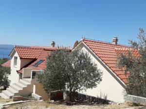 a house with a red roof and stairs at Apartmani Timon in Bol