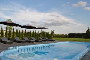 a swimming pool with lounge chairs and umbrellas at Ferienhaus Relax in Kösseln