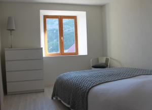 ein Schlafzimmer mit einem Bett, einer Kommode und einem Fenster in der Unterkunft L'Eyssart in Les Vigneaux