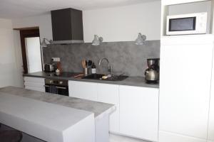 a kitchen with white cabinets and a microwave at Très bel appartement, Parc national des Écrins, piscine et terrasse in Les Vigneaux +18 photos