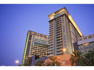 a tall building with palm trees in front of it at Swissôtel Living Al Ghurair in Dubai