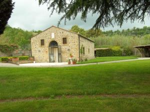 un edificio in pietra in un cortile con erba verde di Il Mulino in Maremma a Farnese