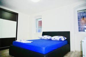 Schlafzimmer mit einem Bett mit blauer Bettwäsche und Kissen in der Unterkunft Puerto Tranquilo beach Residsnce in Trogir