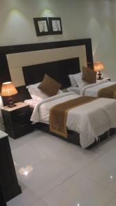 two beds in a hotel room with two lamps at نزل خيال للشقق المخدومه in Abha