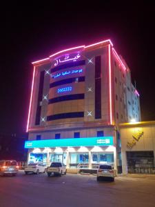 un edificio con coches estacionados en un estacionamiento por la noche en نزل خيال للشقق المخدومه, en Abha