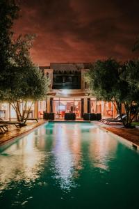 a swimming pool in front of a building at night at Villa Katia in El Harkat