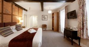 een slaapkamer met een groot bed en een stoel. bij The Talbot Hotel in Ledbury