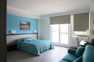 Dormitorio azul con cama y sofá en Sud Est B&B en Palazzolo Acreide