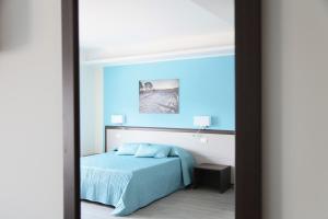 - une chambre avec un lit et un mur bleu dans l'établissement Sud Est B&B, à Palazzolo Acreide