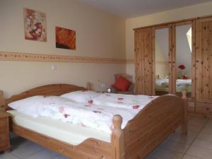 Schlafzimmer mit einem Holzbett mit weißer Bettwäsche in der Unterkunft Ferienwohnungen Gibbert in Pünderich