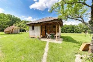 a small cabin with a grass roof on a field at La Clairière du Verbamont in Claudon