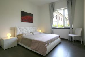 a white bedroom with a bed and a window at Bonnes Vacances a Pietrasanta in Pietrasanta