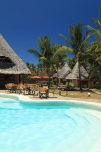 a swimming pool with chairs and tables and palm trees at Crystal Bay Resort in Watamu