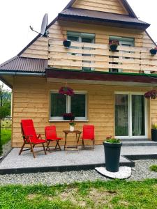 een huis met rode stoelen en een tafel ervoor bij Admi Zakopane in Zakopane