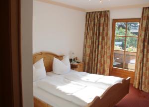 a bedroom with a white bed with a window at Pension Sonnhof in Brixen im Thale