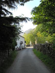 une route vide avec un mur en pierre et un bâtiment dans l'établissement The Langstrath Country Inn, à Keswick