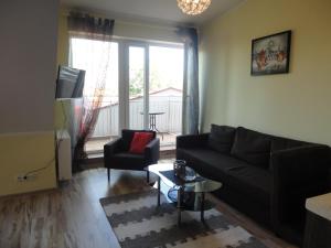 a living room with a black couch and a chair at Apartament Relax in Giżycko