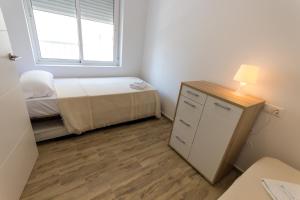 a small bedroom with a bed and a dresser with a lamp at Apartamentos Benidorm Chorrol in Benidorm