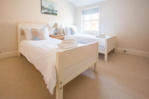 two white beds in a white bedroom with a window at Drift In in Aldeburgh