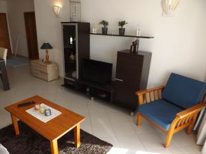 een woonkamer met een stoel, een tafel en een tv bij Vila Gaivota Mare Azur in Ferragudo