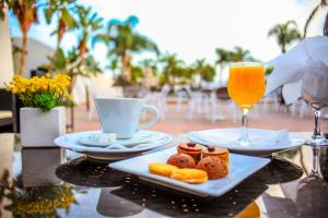 盖尼特拉Assam Hotel的桌子上有两盘食物和一杯橙汁