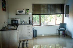 a kitchen with a sink and a microwave and a window at 21 on Klein Karoo in Oudtshoorn
