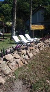 een rij witte ligstoelen in een rotswand bij Pousada Canto da Galheta in Ilha do Mel