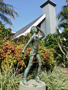 
a statue of a man standing on top of a lush green field at Serendipity Country House & Restaurant in Wilderness
