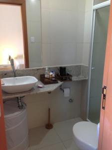 a bathroom with a sink and a toilet and a mirror at 3 Suítes, praia e piscina in Itacimirim