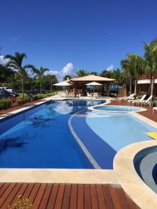 a large swimming pool with blue water in a resort at 3 Suítes, praia e piscina in Itacimirim