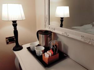 ein Tablett mit Tassen und einer Kaffeekanne auf einem Tisch mit zwei Lampen in der Unterkunft Lady Luna B&B in Florenz