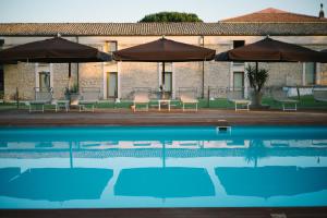 a pool with chairs and umbrellas next to a building at Hotel Villa Carlotta in Ragusa