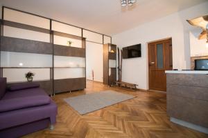 a living room with a purple couch and a kitchen at Poarta Schei apartment in Braşov