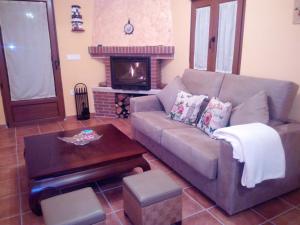 Casa Rural El Abuelo Anselmo في سيغوفيا: غرفة معيشة مع أريكة ومدفأة