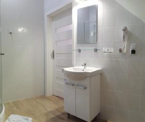 a white bathroom with a sink and a mirror at Domus in Ustka