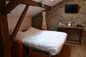 a bedroom with a bed and a table with a tv at Auberge Le Temps des Saveurs in Paliseul