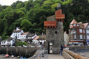 a person standing in front of a building next to a town at Postmans Rest, second floor apartment, Lynmouth with private parking in Lynmouth