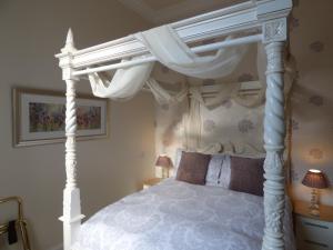 a bedroom with a white canopy bed with curtains at Douglas Park Guest House in Dunoon